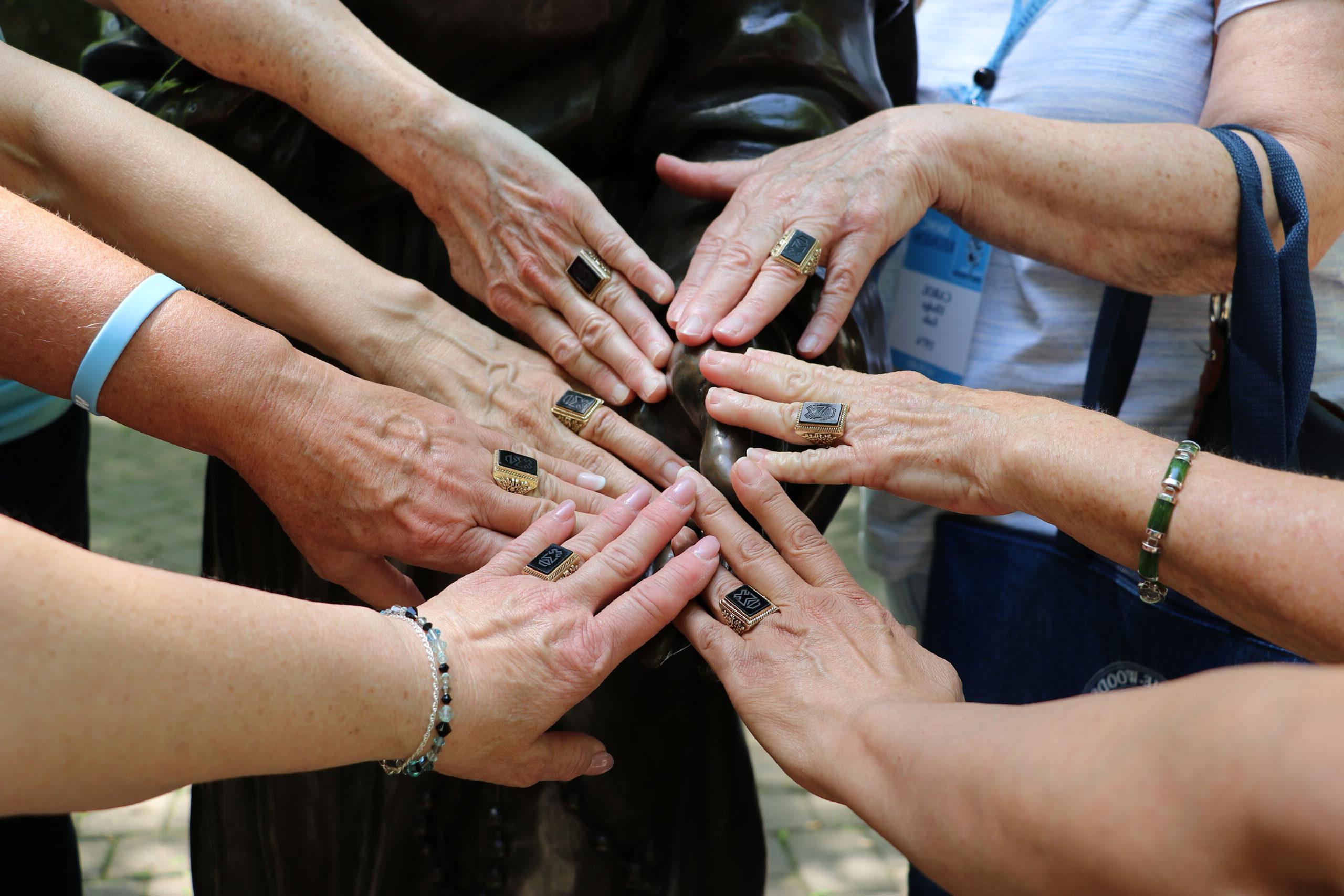 Alums putting their hands together with Woods Rings at Reunion